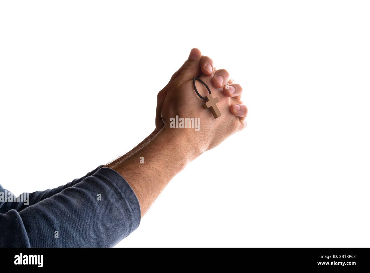 Man praying in church with his hands closed and with pendant with cross symbol in his hand and flash. Horizontal composition Stock Photo