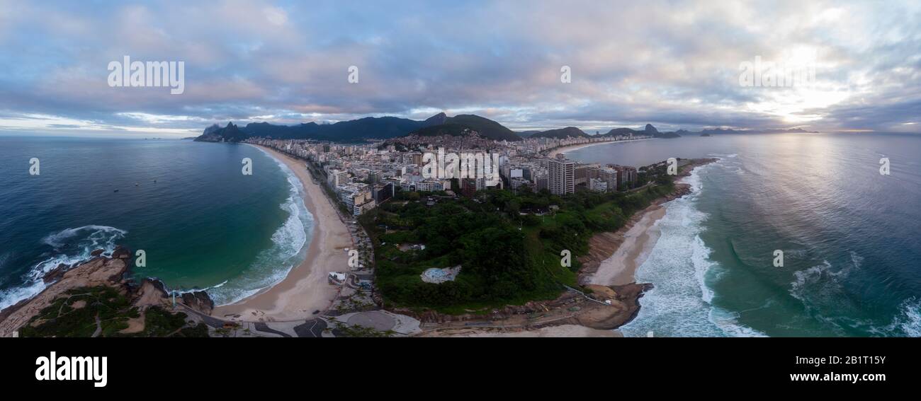 Arpoador rock in Rio de Janeiro with Ipanema and Copacabana beach on either side and wider cityscape in the background against an overcast sky Stock Photo