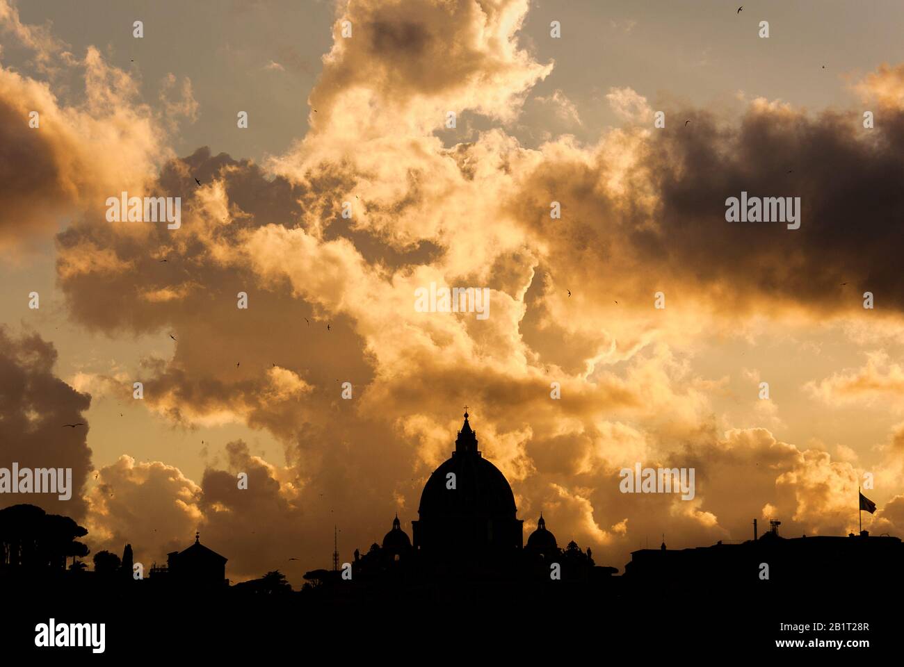 Beautiful sunset sky and clouds over Rome historic center skyline with the famous and iconic St Peter's Dome Stock Photo