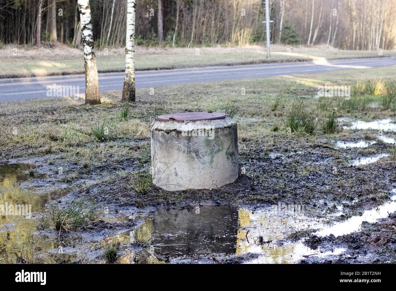 Old well in a puddle by the road Stock Photo - Alamy