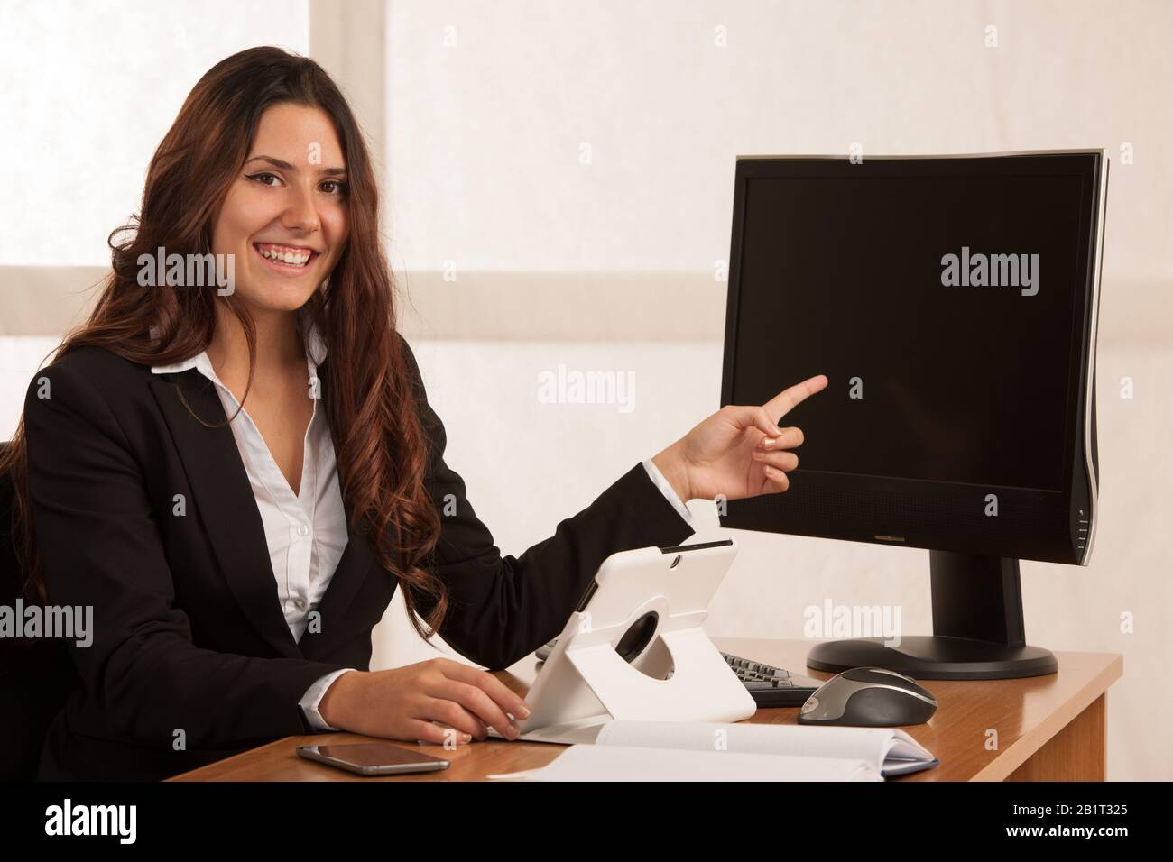 Beautiful business woman in her office with blank space on her monitor for additional text or graphic Stock Photo