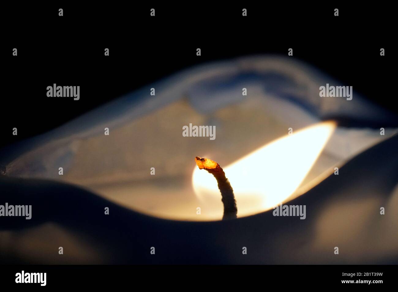 The closeup-macro photography of a burning candle light pointing to the right, isolated on the black background Stock Photo
