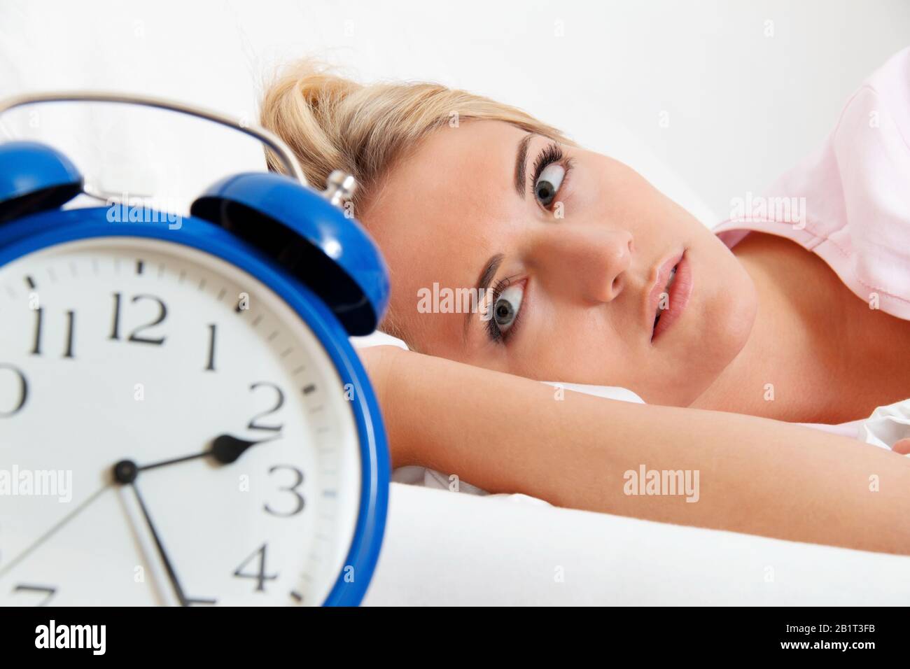 Junge Frau aegert sich beim Aufwachen und Aufstehen um 2.30 Uhr. Stock Photo