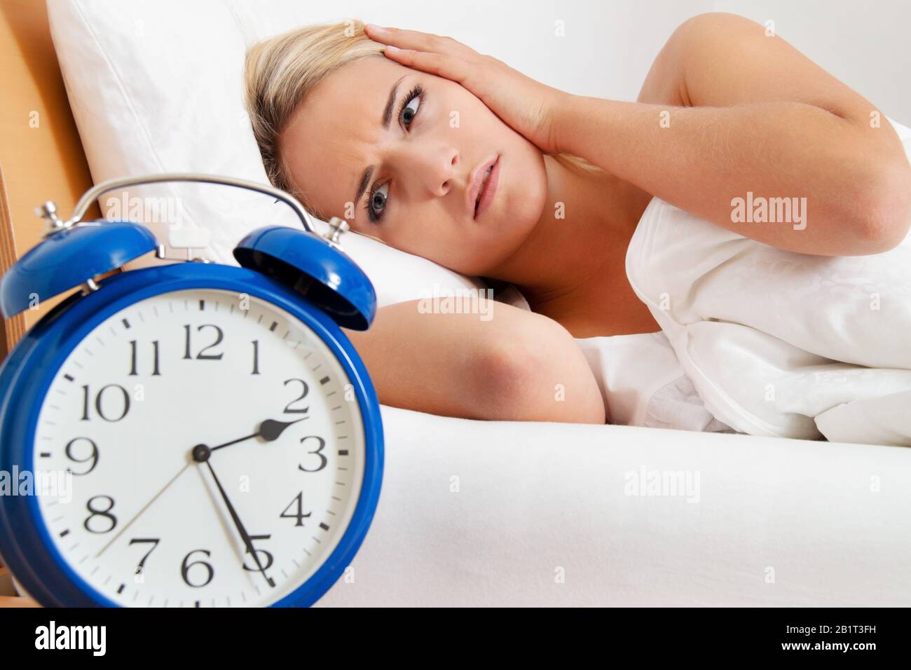 Junge Frau aegert sich beim Aufwachen und Aufstehen um 2.30 Uhr. Stock Photo