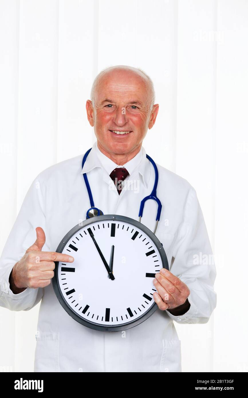 Ein Arzt haelt eine Uhr. Auf dem Ziffernblatt ist es 5 Minuten vor 12, Coronavirus, MR: Yes Stock Photo