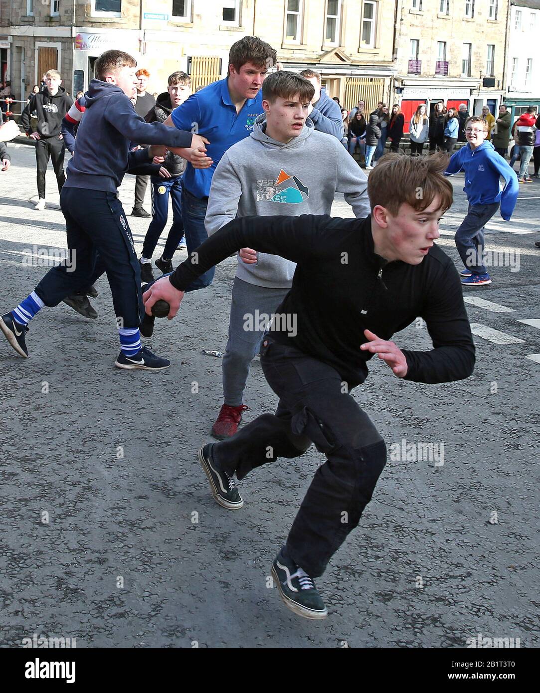 Boys tussle for the leather ball during the annual Jedburgh ba' game event on Jedburgh's High Street in the Scottish Borders. Picture date: Thursday February 27, 2020. The annual event started in the 1700s and the first ever game was supposedly played with an Englishman's head. It involves two teams, the Uppies (residents from the higher part of Jedburgh) and the Doonies (residents from the lower part of Jedburgh) getting the ball to either the top or bottom of the town. The ball, which is made of leather, stuffed with straw and decorated with ribbons representing hair, is thrown into the crow Stock Photo