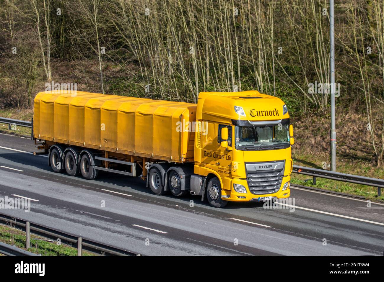 David Curnock Ltd yellow Haulage delivery trucks, lorry, transportation, truck, cargo carrier, DAF vehicle, commercial transport, industry, M61 at Manchester, UK Stock Photo