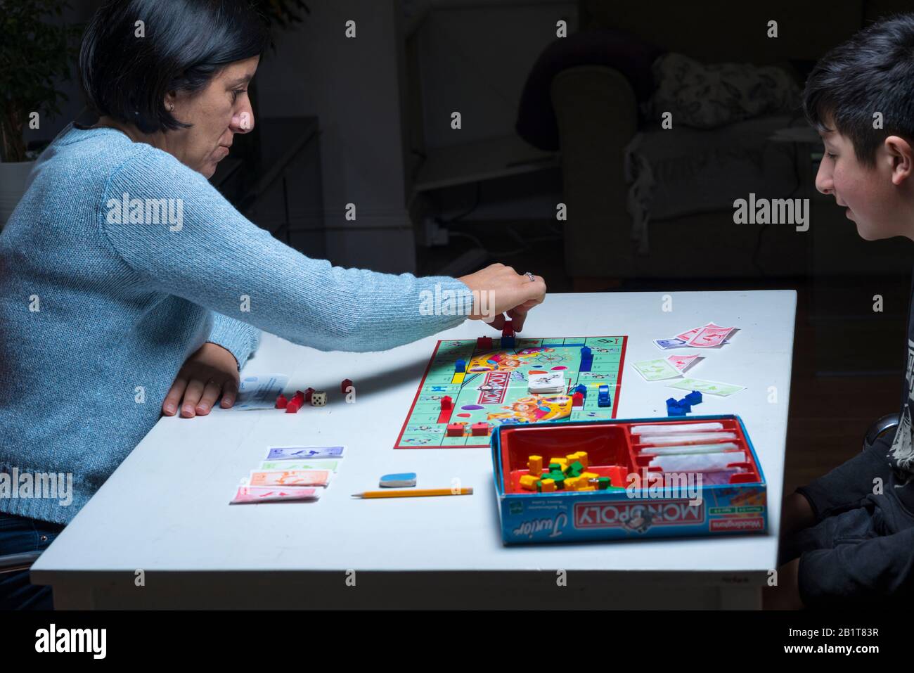 Mother and her teenage son playing monopoly board game together Stock Photo
