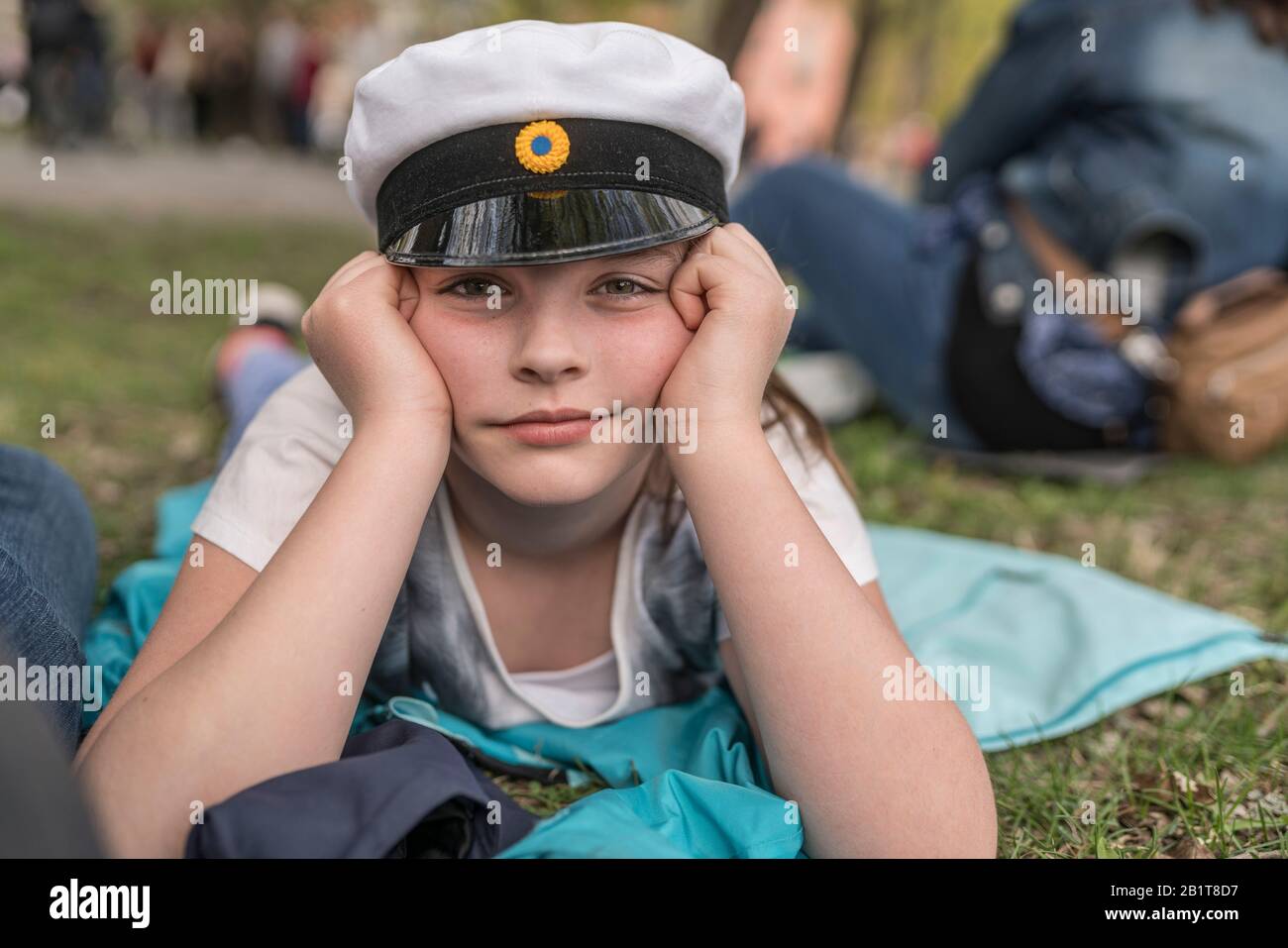 Portrait of a young girl with a traditional student hat lying on the ground at the Valborg celebration in Uppsala, Sweden Stock Photo