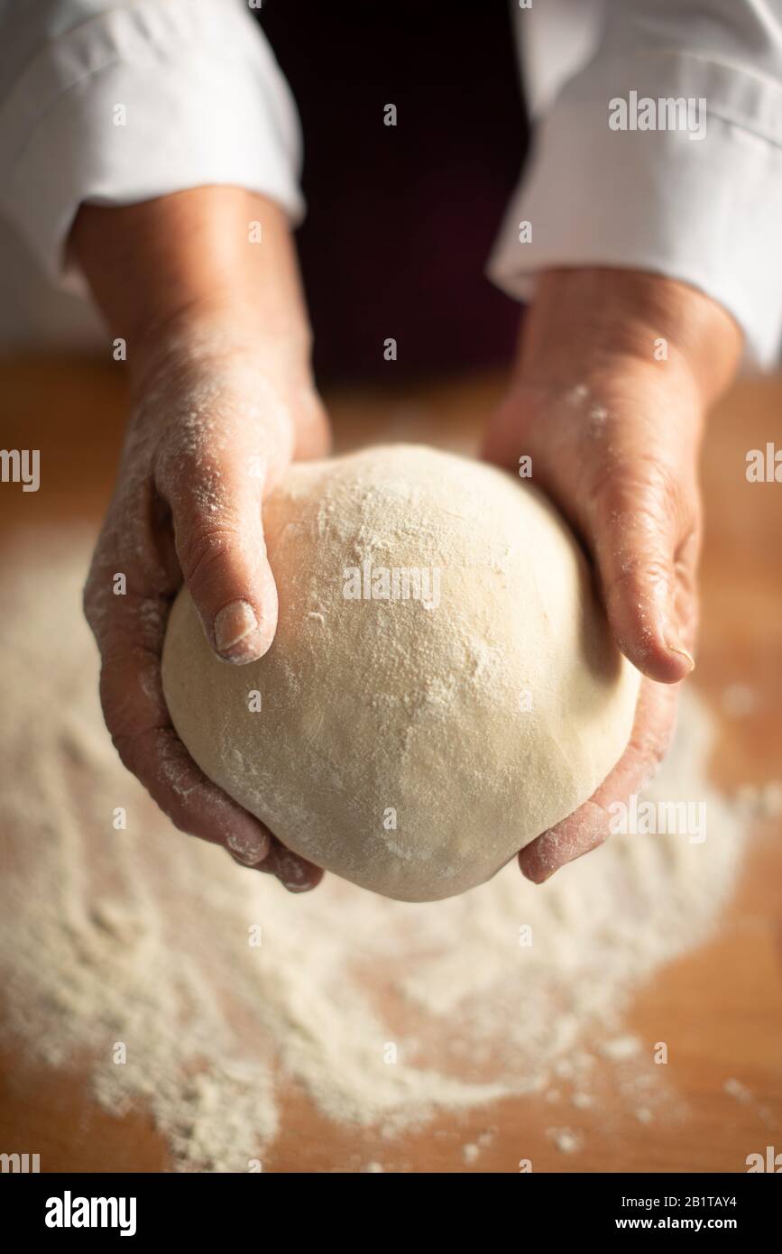 Bakery- clos-up of a bakers holding a sourdough ball of dough  in preparation of artisan bread,London,UK Stock Photo