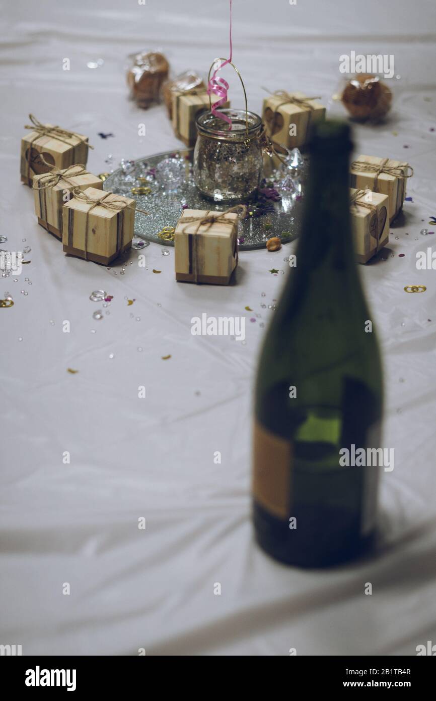 selective focus on a centrepiece on a wedding reception table with a bottle of champagne out of focus in the foreground Stock Photo