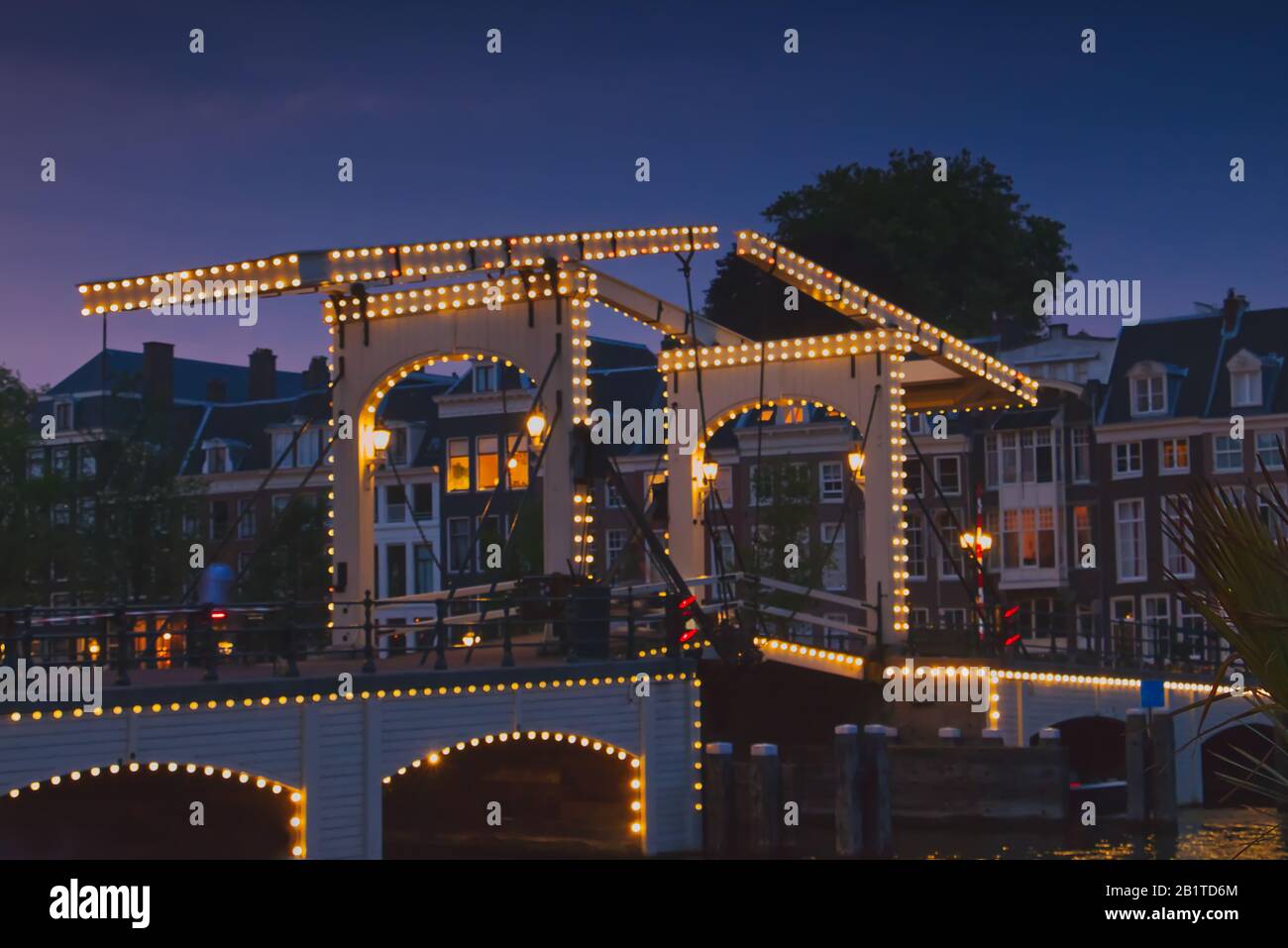 Magere Brug (Skinny Bridge) illuminated at sunset over the river Amstel in Amsterdam, Netherlands Stock Photo