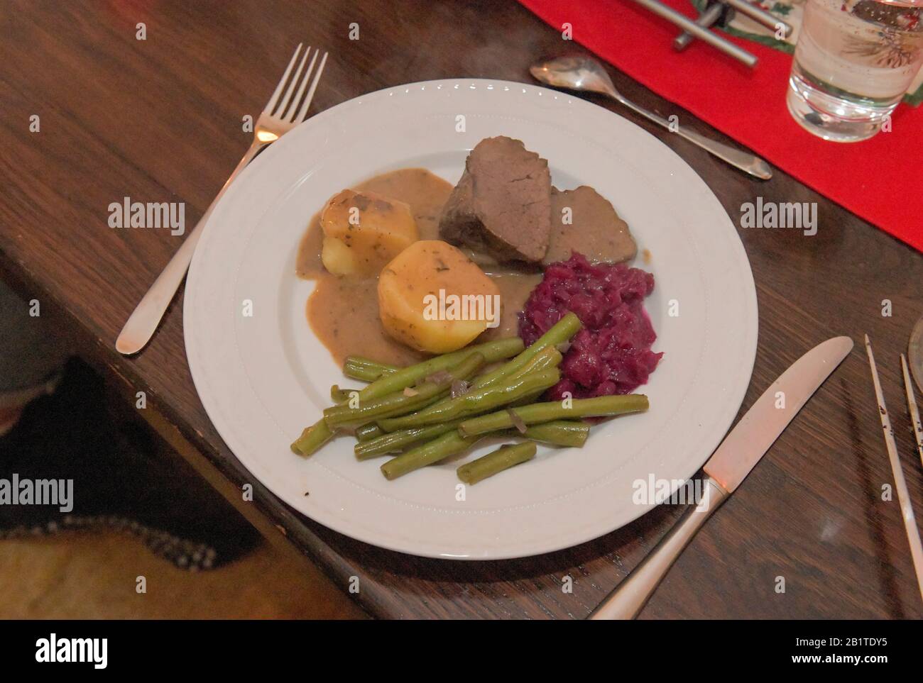 Teller Hirschbraten mit Rotkohl, Bohnen, Kartoffeln Stock Photo