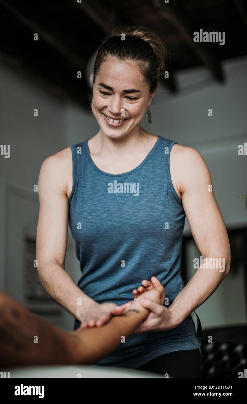 Smiling massage therapist treats her patient's hand and arm Stock Photo