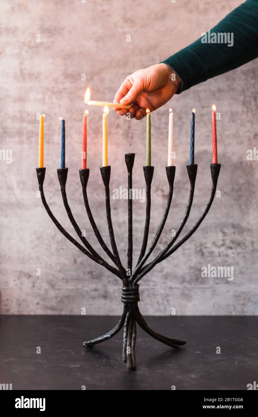 Cropped image of a hand lighting candles on menorah for Hanukkah. Stock Photo