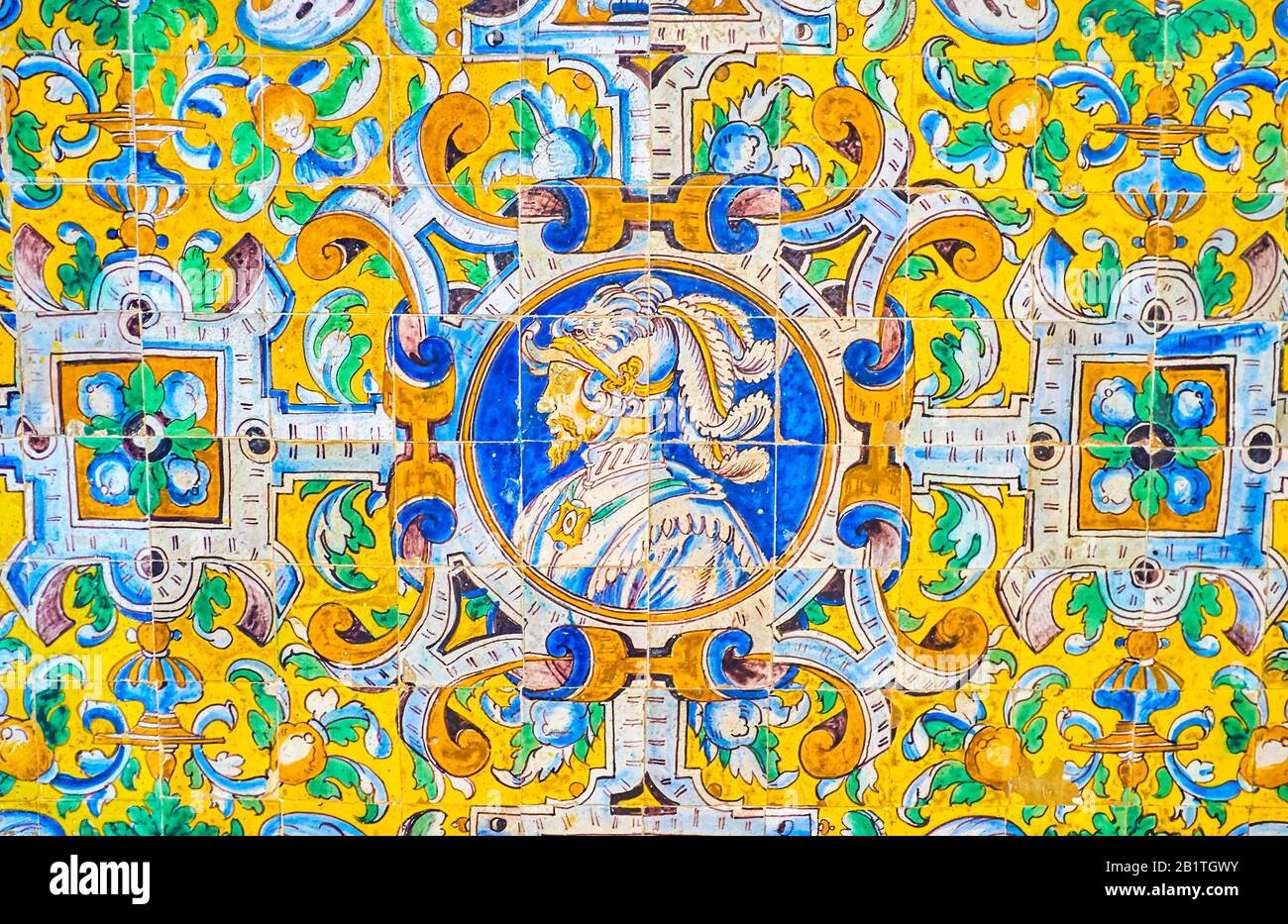 The amazing glazed tiled wall on Alcazar Palace complex depicting the face of the knight in armot surrounded with floral ornament, Seville, Spain Stock Photo