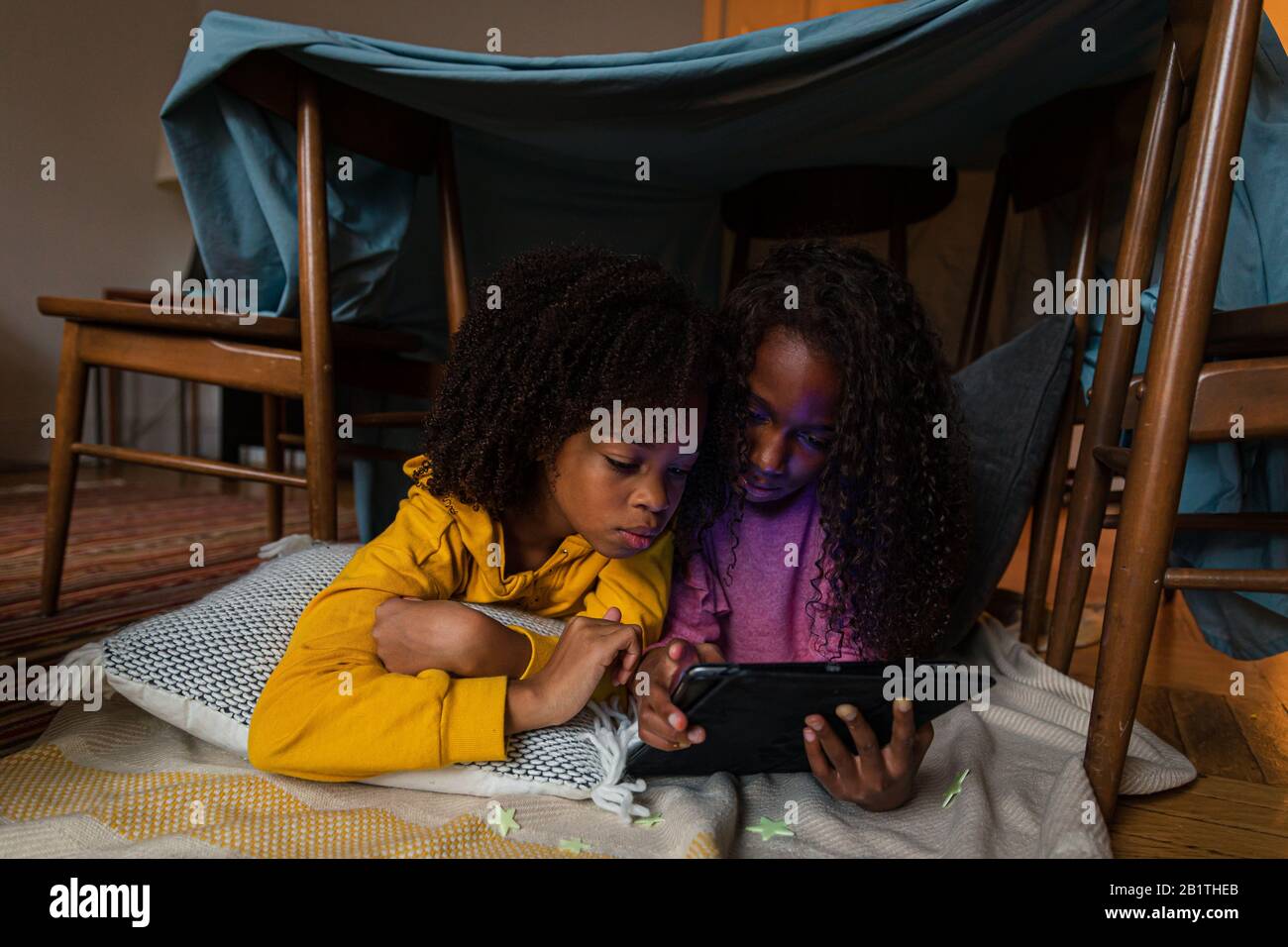 Sisters using digital tablet while lying at home Stock Photo