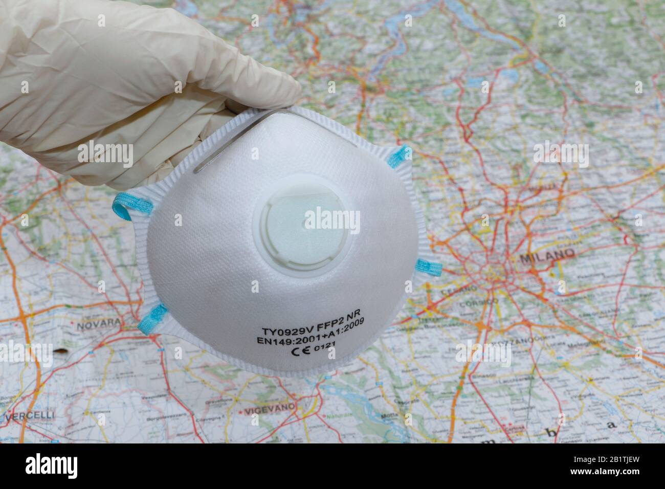 FREIBURG, GERMANY - FEB 24, 2020: A medical mask and medical gloves on a map of northern Italy / Milan representing the outbreak of corona Stock Photo