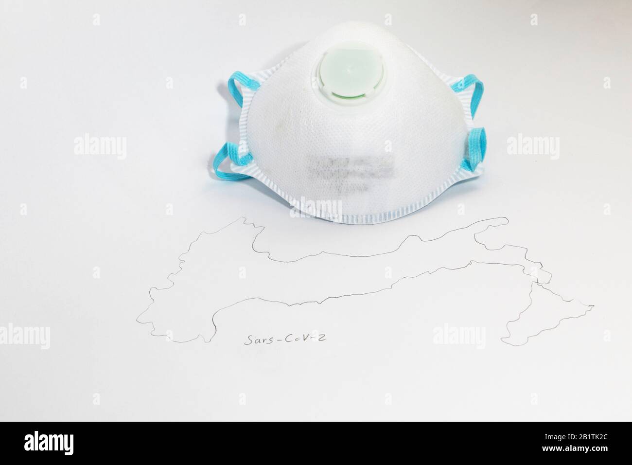 FREIBURG, GERMANY - FEB 24, 2020: A medical mask type FFP2 next to a symbolic map of italy representing the outbreak of the new corona virus / SARS Stock Photo