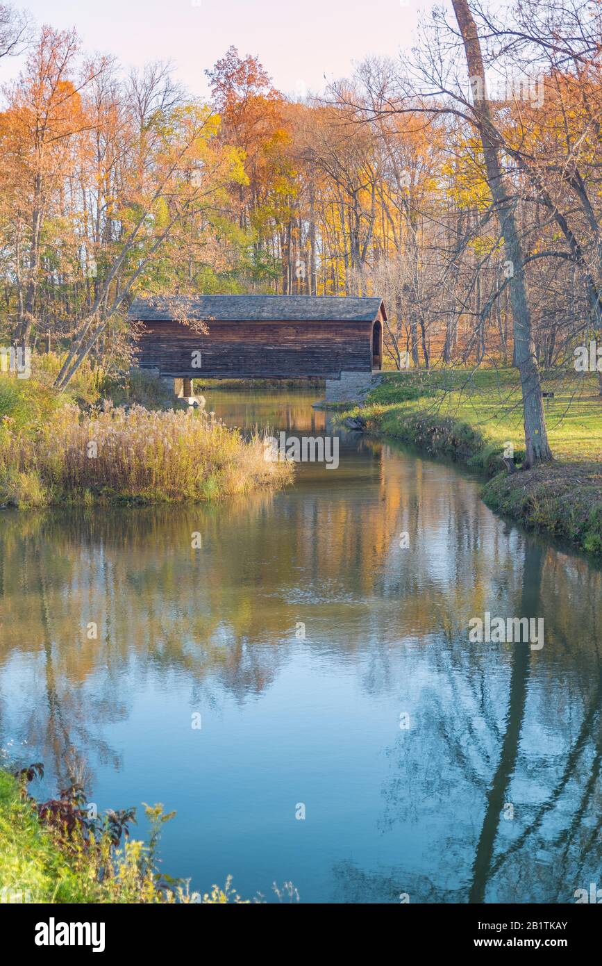 Covered bridge in the autumn with reflections in a creek Stock Photo
