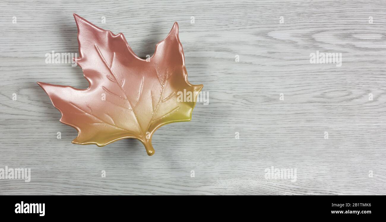 Ceramic autumn maple leaf on a white wooden background Stock Photo