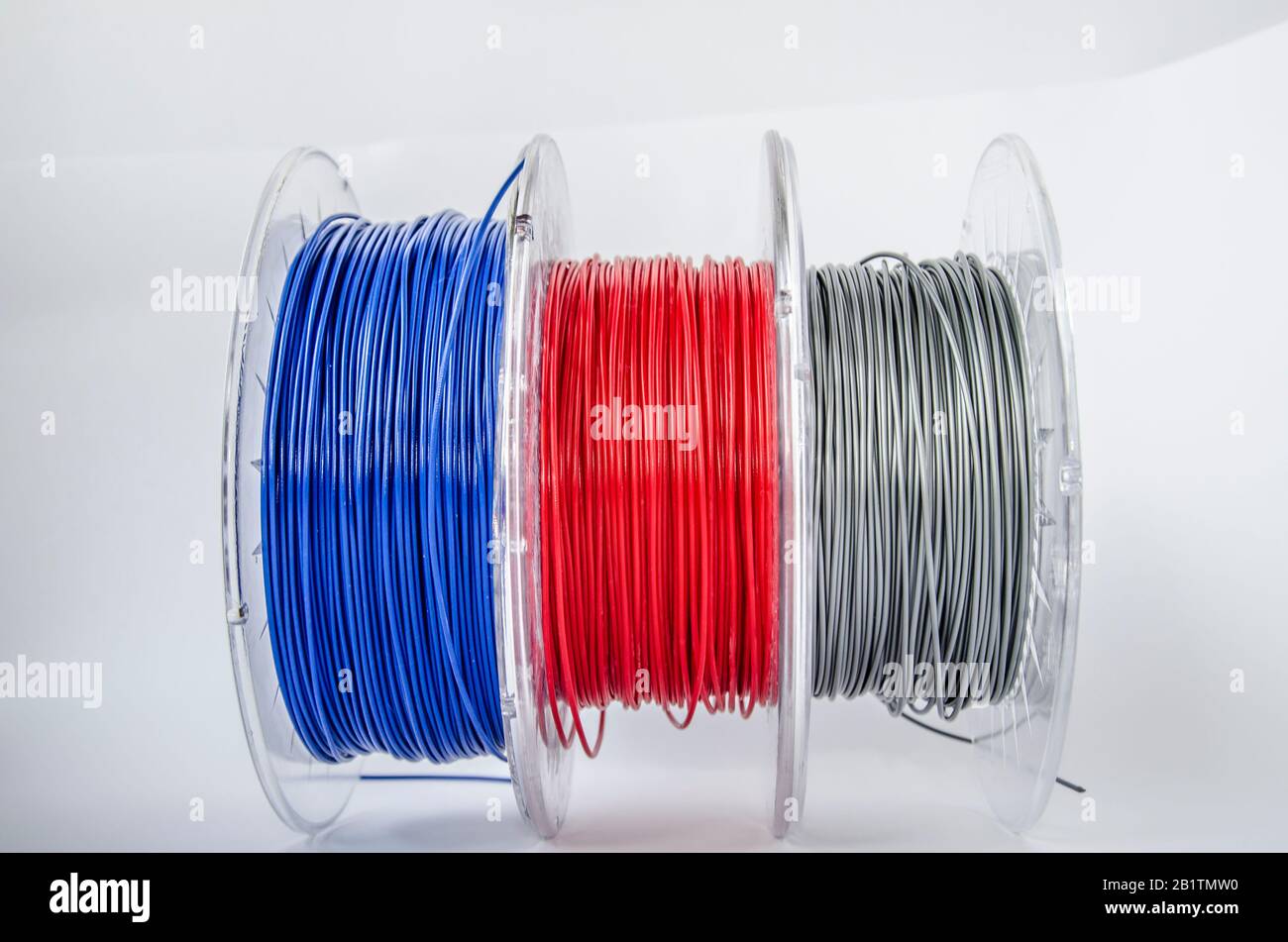 Plastic for 3D printing. Red, silver and blue plastic filament, ABS/PLA coil for 3d printer on white background, isolated Stock Photo