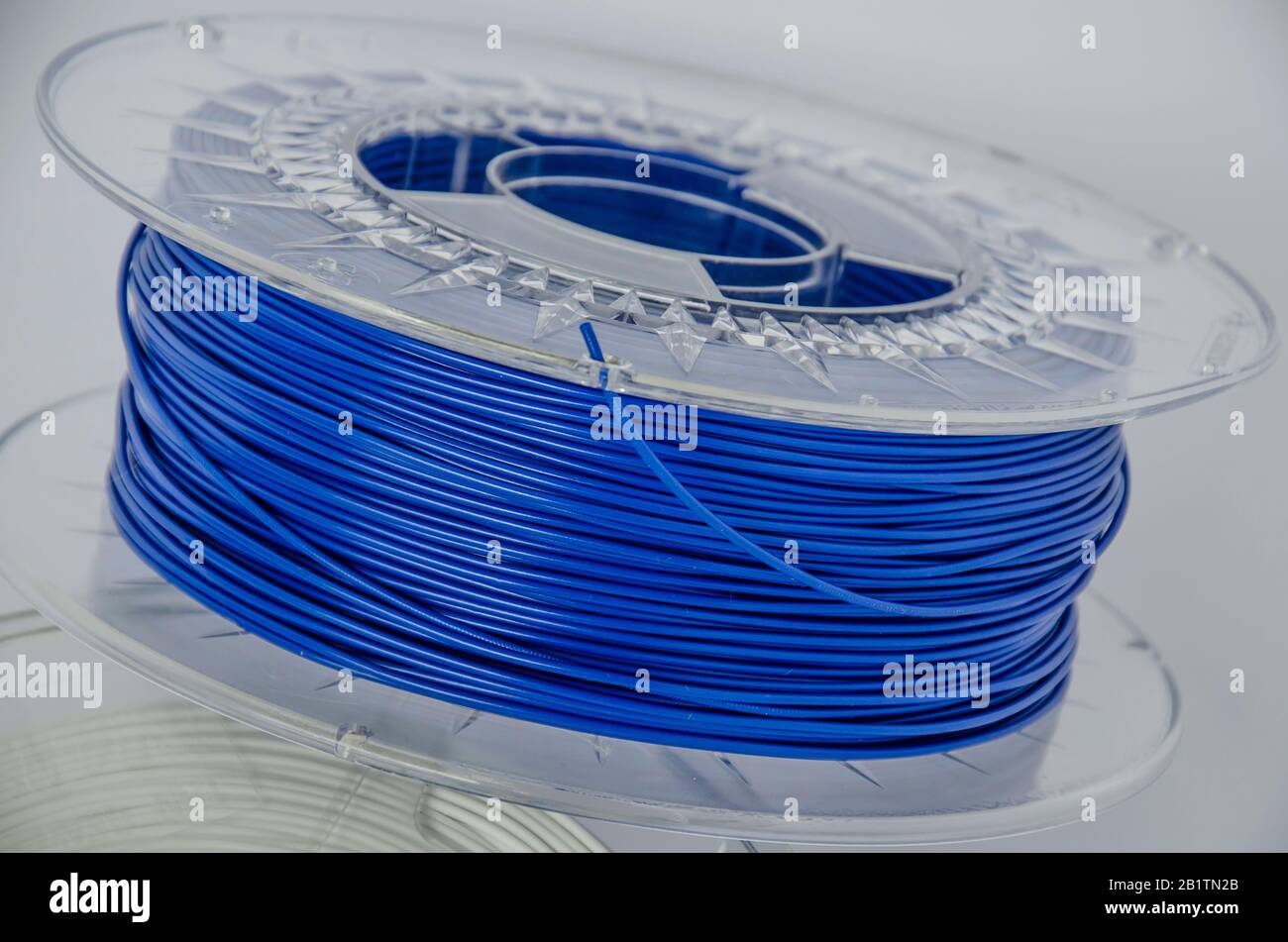 Plastic for 3D printing. Blue plastic filament, red ABS/PLA coil for 3d printer on white background, isolated Stock Photo