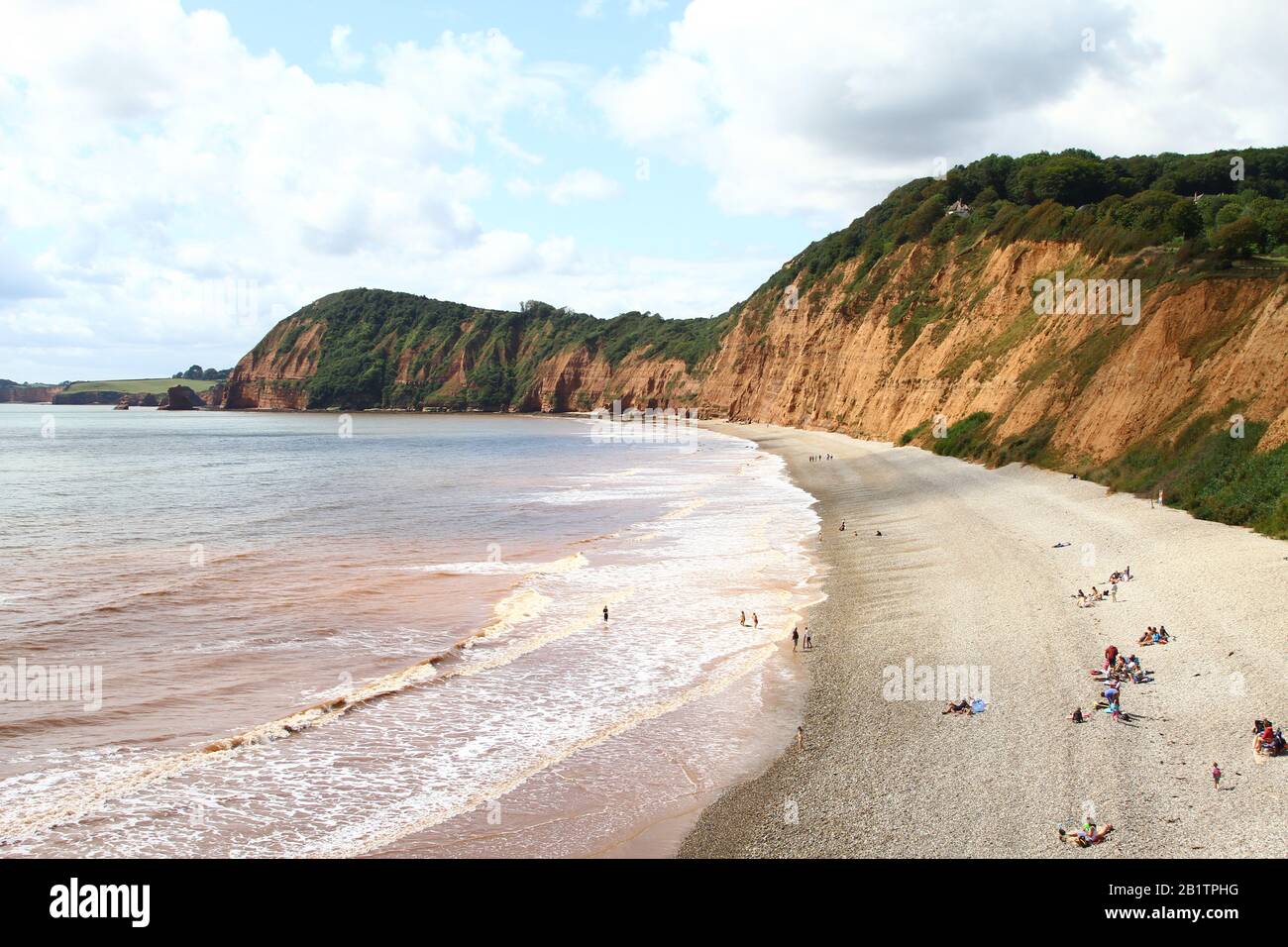 Staycation United Kingdom. Beach scene at Sidmouth, Devon, England. People enjoying the good weather in the South West of England who have decided to reduce their Carbon foot print by not travelling to far flung destinations. Sidmouth is a small coastal town situated of the Jurassic coast. A large part of the town has been designated a conservation area and the Jurassic coast a World heritage site. Stock Photo