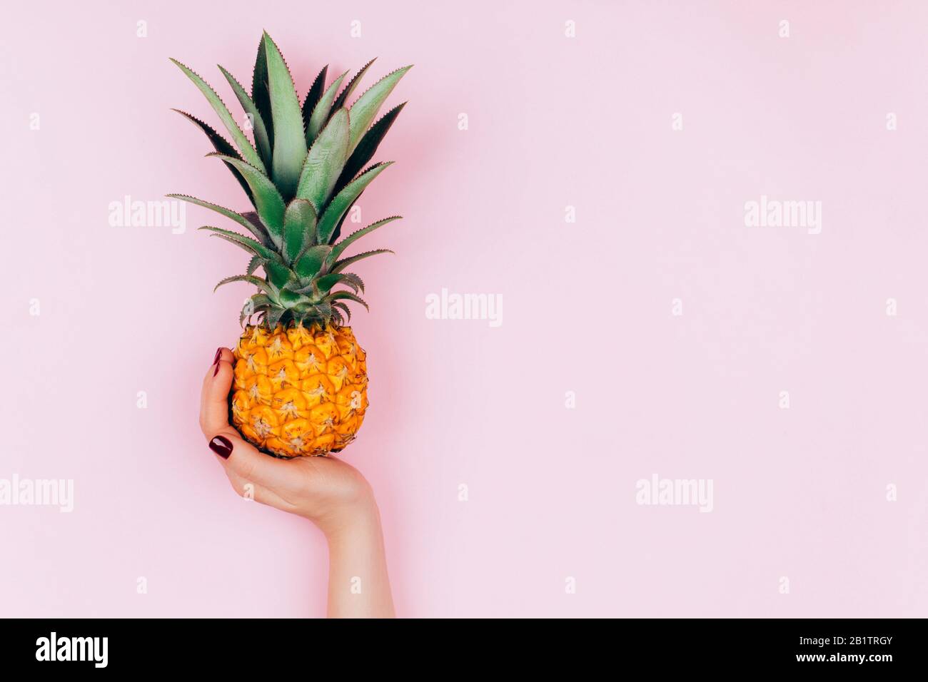 Hands with pineapple on stylish pink background. Stock Photo