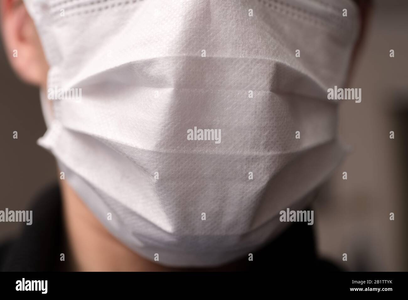 Closeup with the face of a young man wearing medical or surgical mask ...