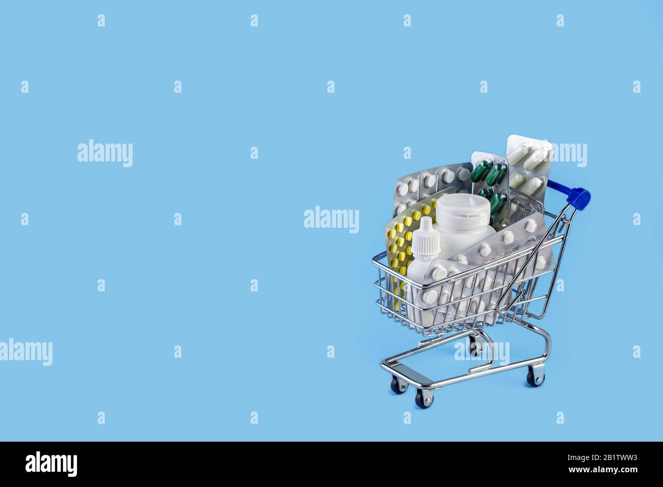 Buy and shopping medicine concept. Various capsules, tablets and medicine in shop trolley on a blue background. Shopping cart with pills. Copy space Stock Photo