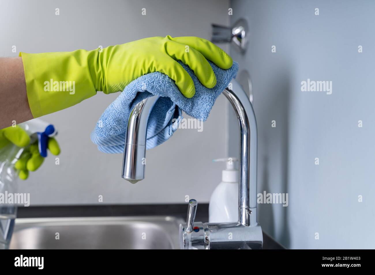 Young Man Cleaning The Steel Tap In The Kitchen Stock Photo