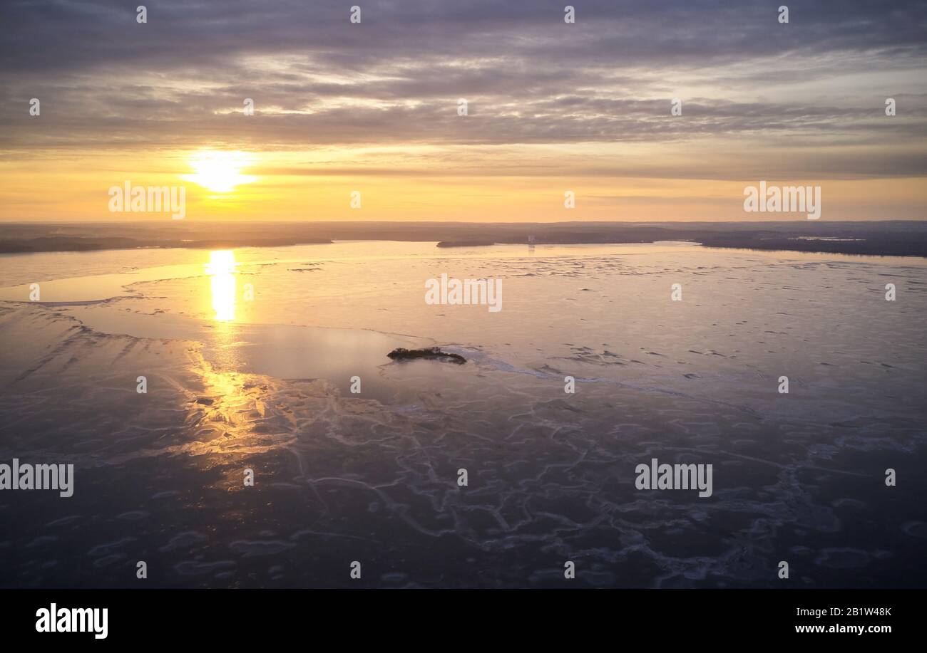 Dusk at frozen lake aerial drone view. Ice melting on river Stock Photo