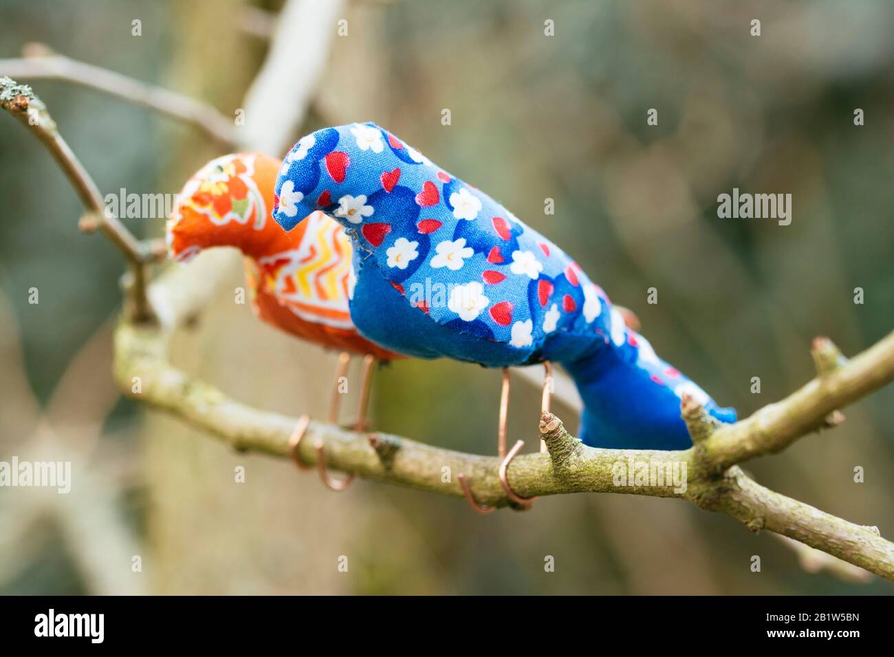 Two hand made bird softies on a branch in the garden. Stock Photo