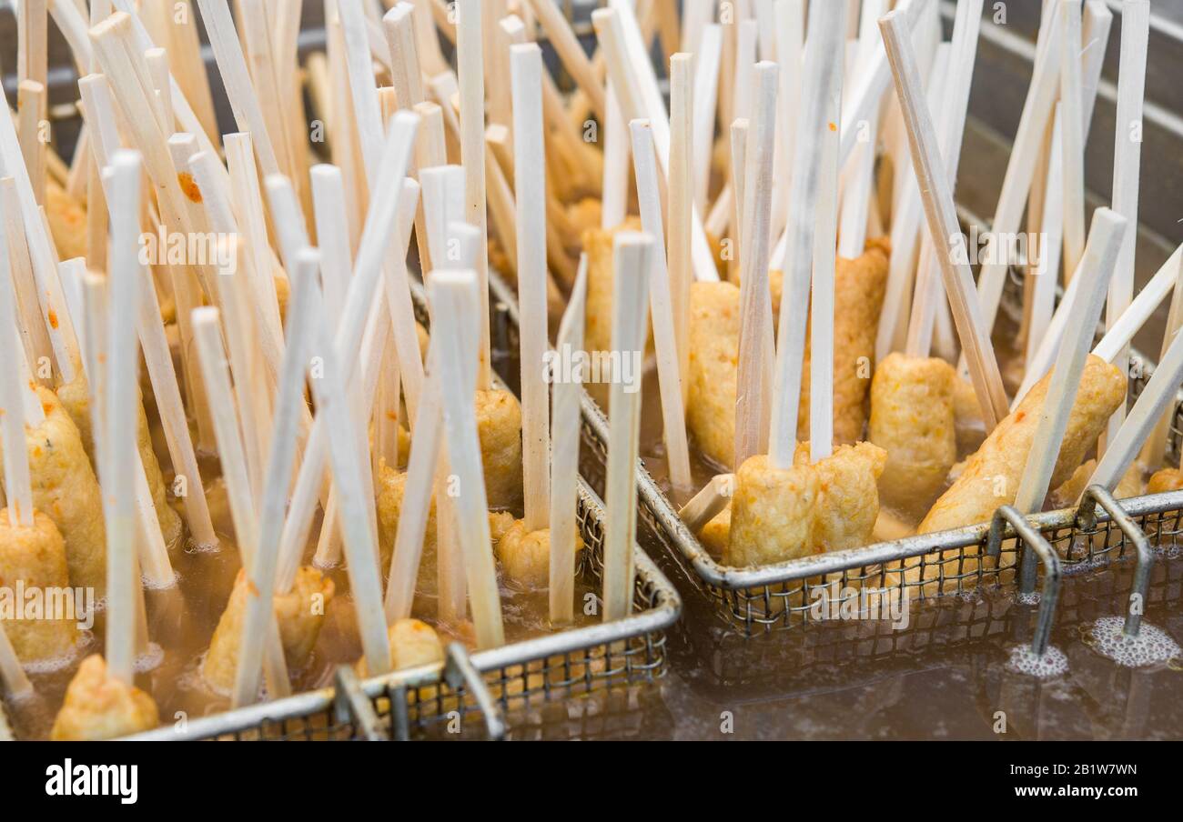 Traditional South Korean corn dogs frying in hot oil at a street food market. Stock Photo