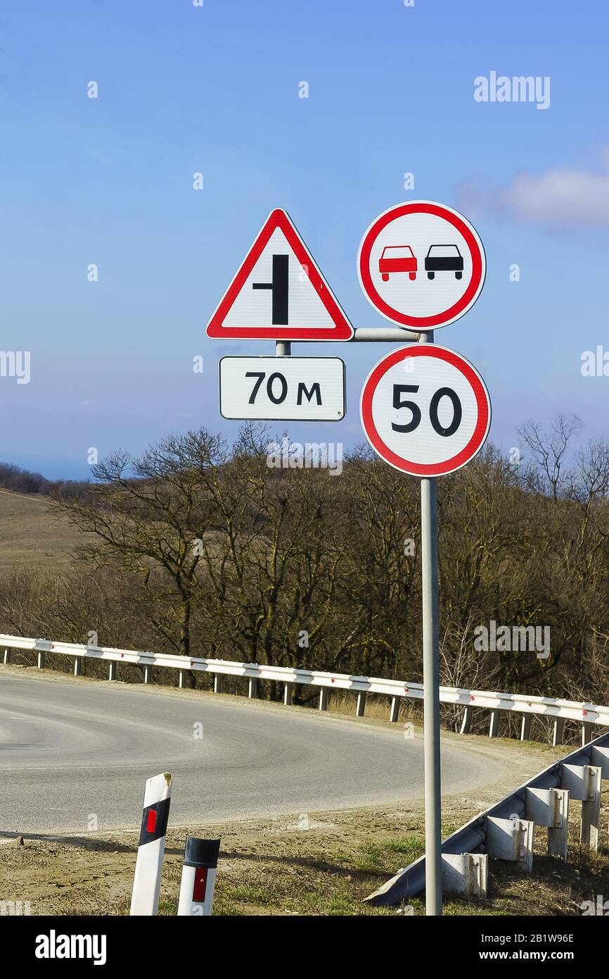 Road signs, speed limits and ban on overtaking at a sharp turn of the highway. The rules of the road Stock Photo