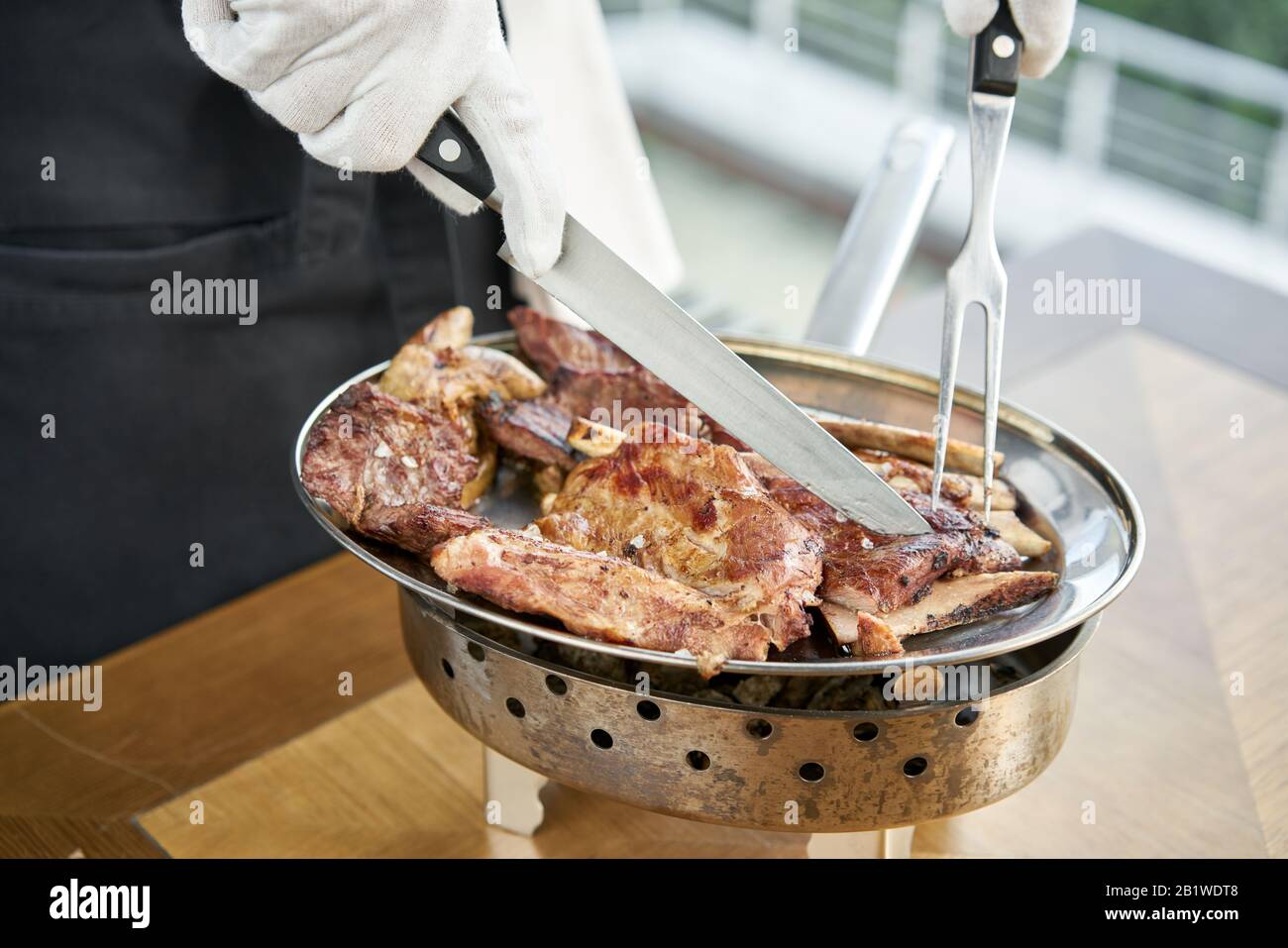 The waiter is butchering with a knife. Various grilled meat set