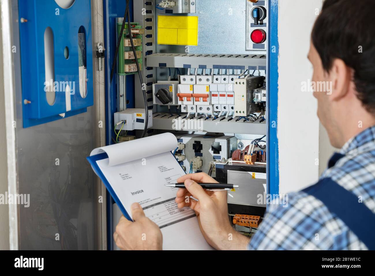 Cropped Image Of Male Electrician Holding Clipboard While Examining Fusebox Stock Photo