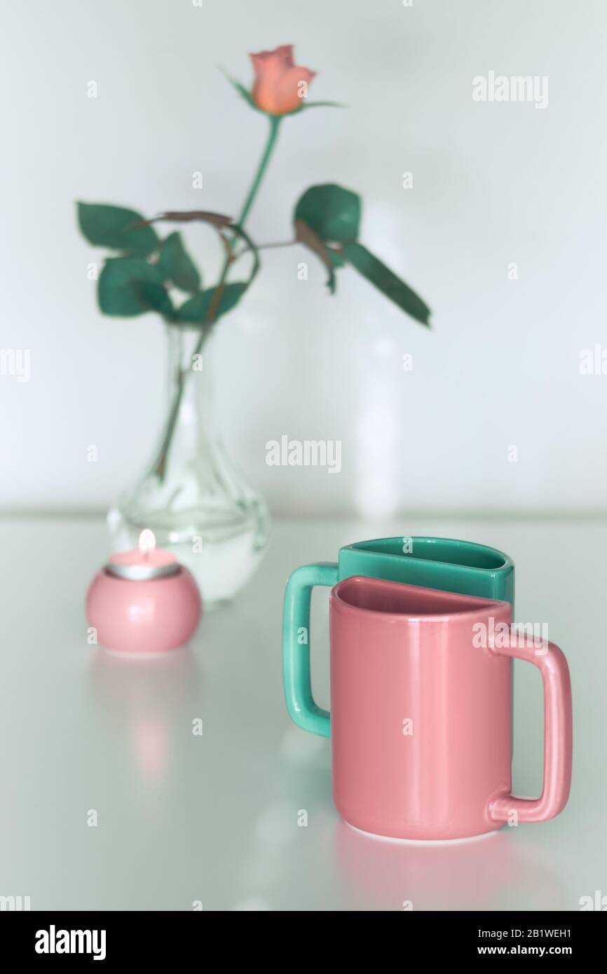Pink rose flower and twin half tea mugs in salmon pink and fresh mint green. Minimalist design for your house in pastel colors. Modern interior decor, Stock Photo