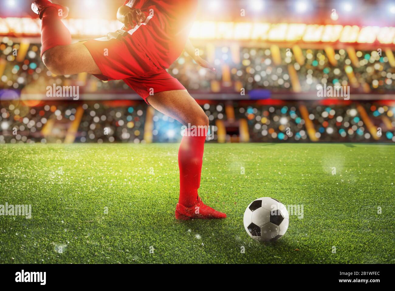Football scene at night match with player kicking the ball with power. Stock Photo