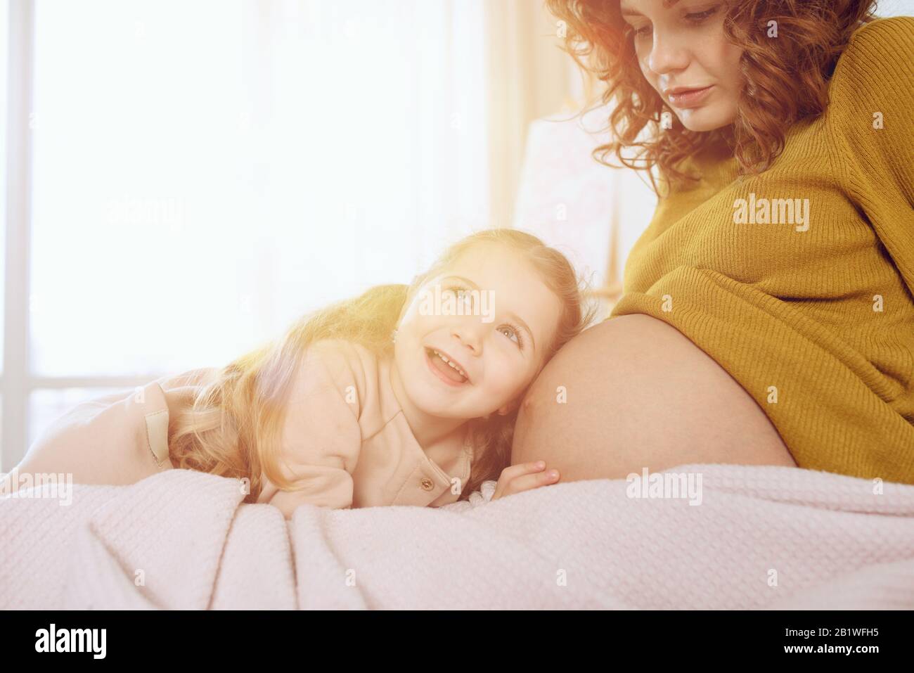 Pregnant mom plays with her daughter. Concept of family, joy and pregnancy Stock Photo