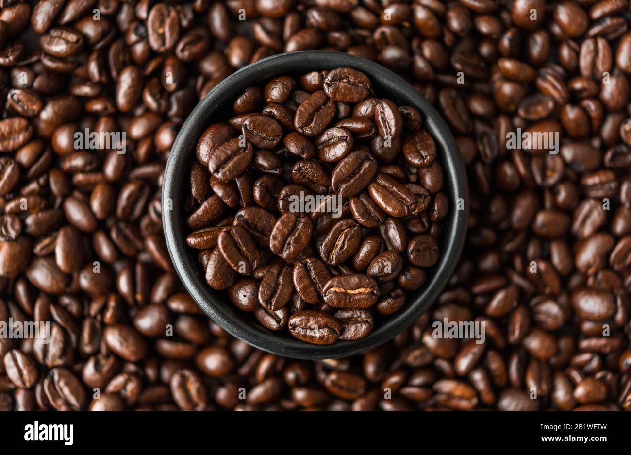 Roasted coffee beans in a black bowl. Stock Photo