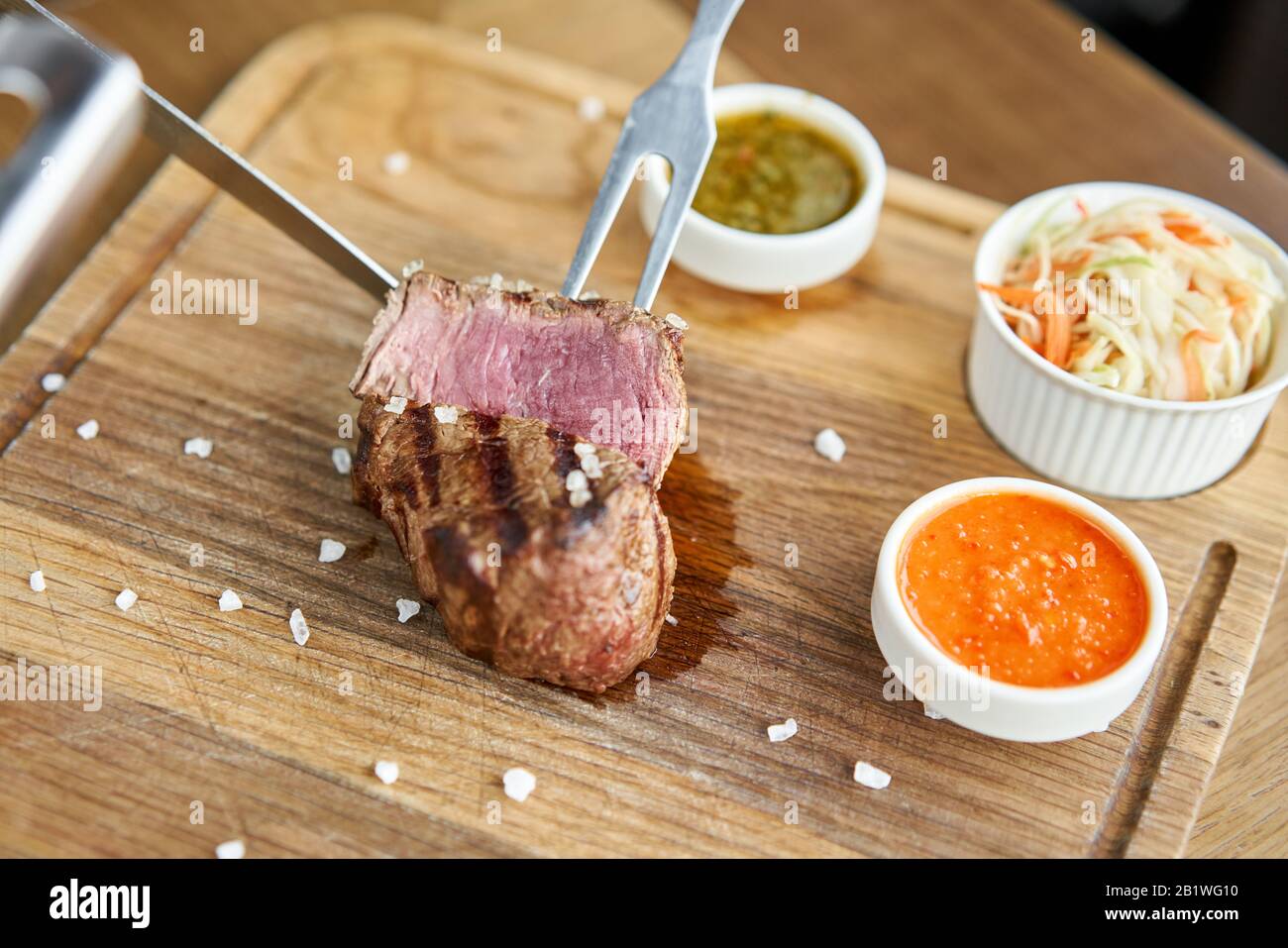 The waiter is butchering griled meat with a knife. Fried dry aged beef