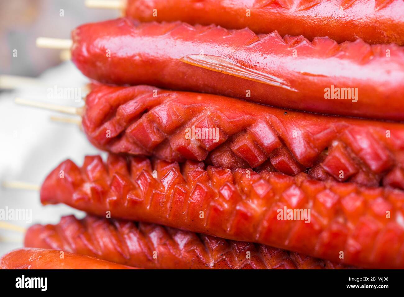 Grilled barbecued sausage hot dogs on a stick at a street food market. Stock Photo