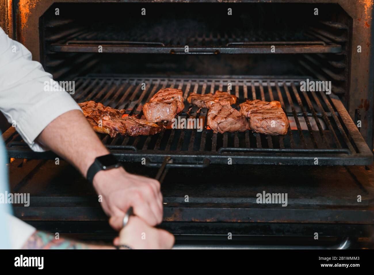 Chef cooking beef steaks on a charcoal grill pan Stock Photo - Alamy