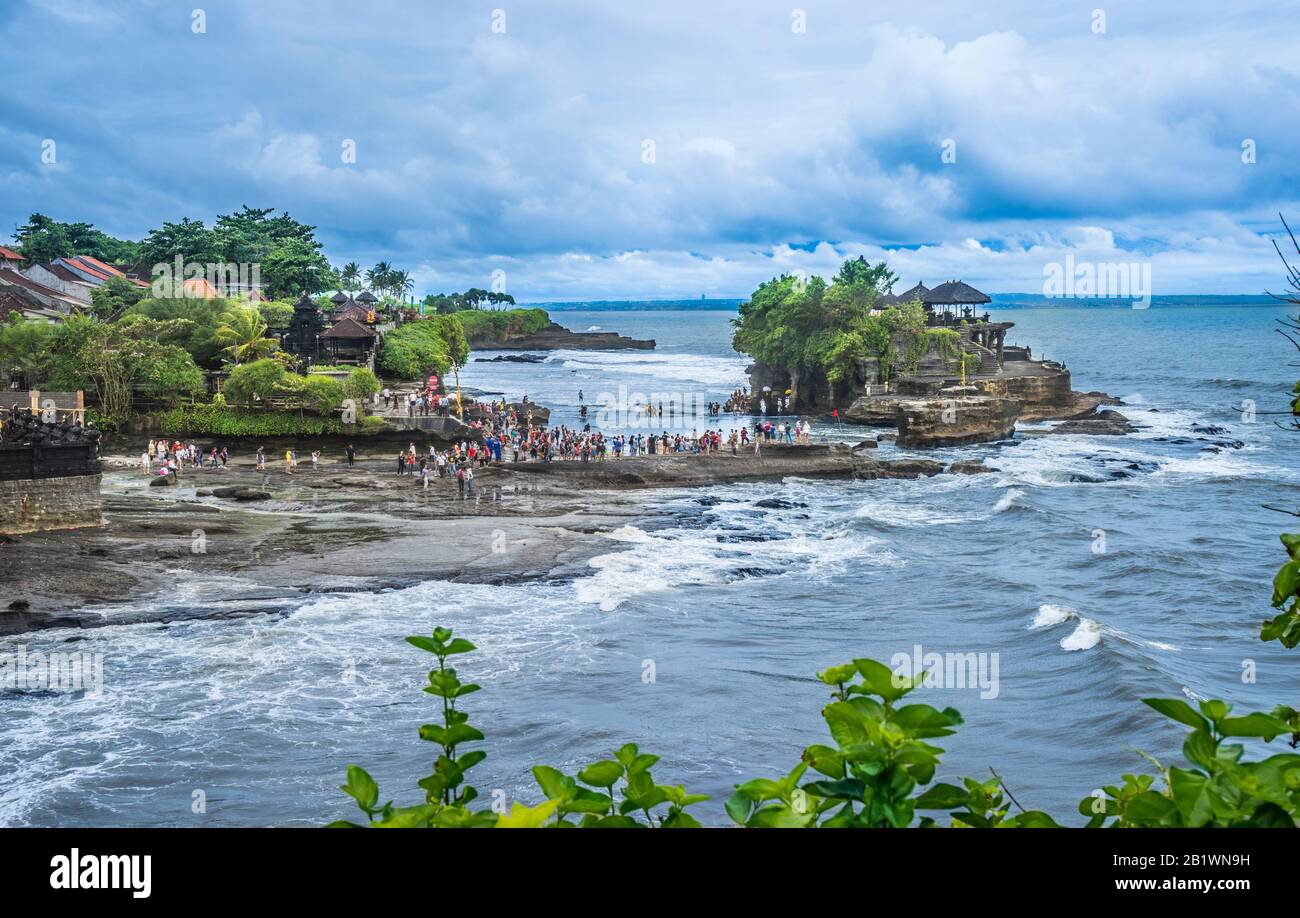 visitors and pilgrims at Tanah Lot, a rock formation off the Indonesian island of Bali, home to an ancient Hindu pilgrimage temple Pura Tanah Lot, Bal Stock Photo
