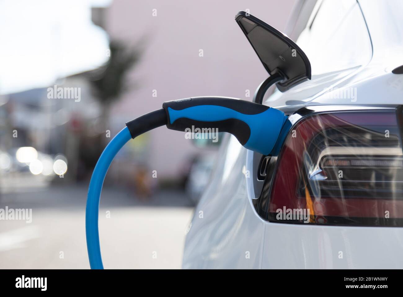 EV electric car pluged charging at a recharge station in the city Stock Photo