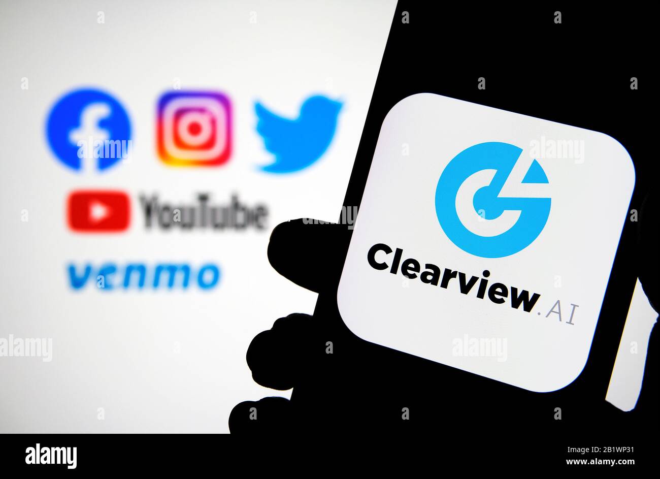 Clearview AI company logo on the smartphone hold in hands with blurred social media where the data collected. Concept for face recognition software. Stock Photo