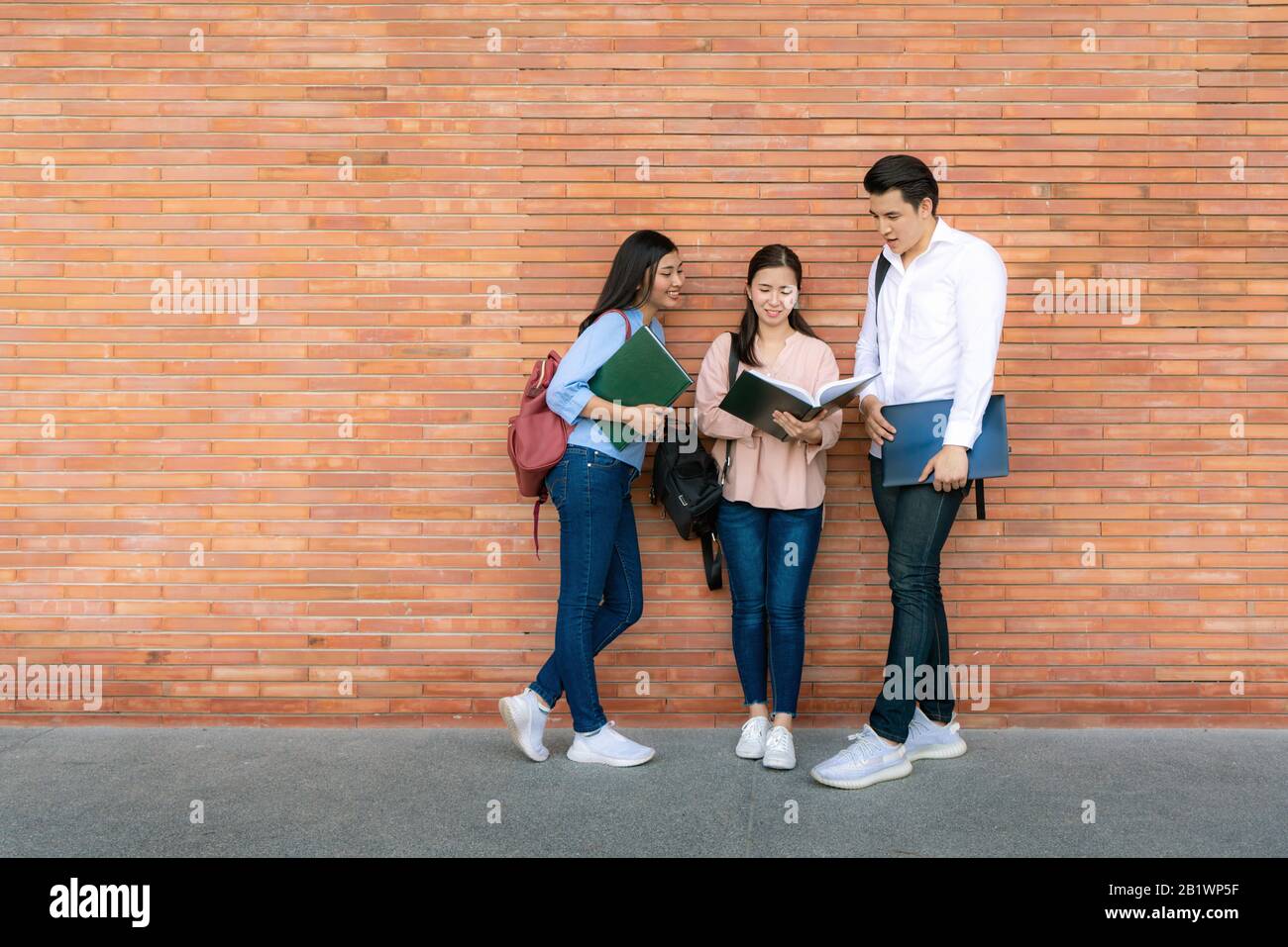 Three Asian students are discussing about exam preparation, presentation, study, study for test preparation in University. Education, Learning, Studen Stock Photo