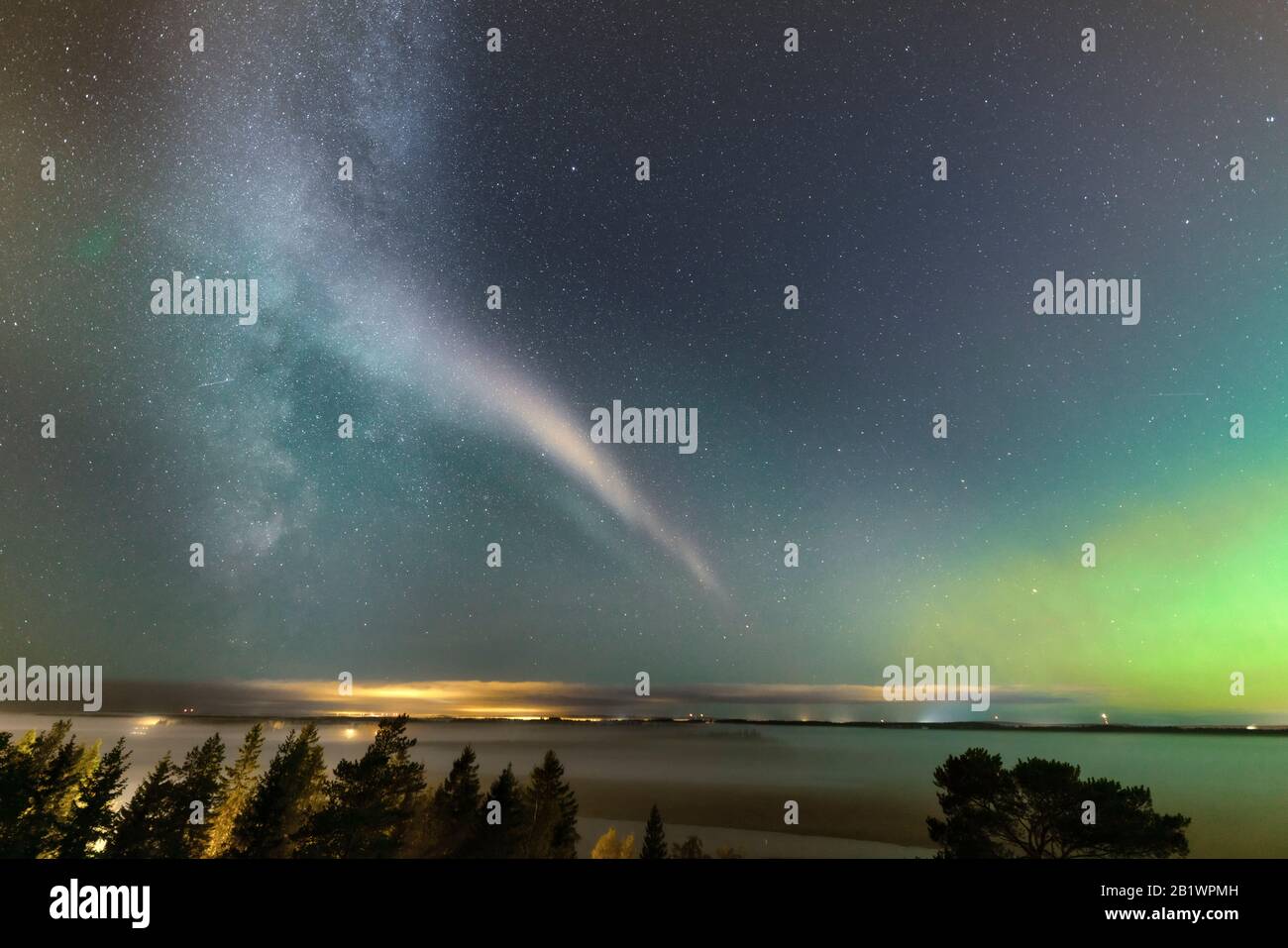 Weak Northern Lights on horizon and atmospheric phenomenon 'STEVE' crossing Milky Way. Steve appears as a purple and green light ribbon in the sky at Stock Photo